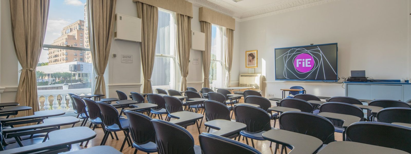 A large classroom at Foundation House with tall windows and a wall-mounted touchscreen